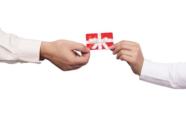Closeup shot of two people holding a red gift card on a white Free Photo